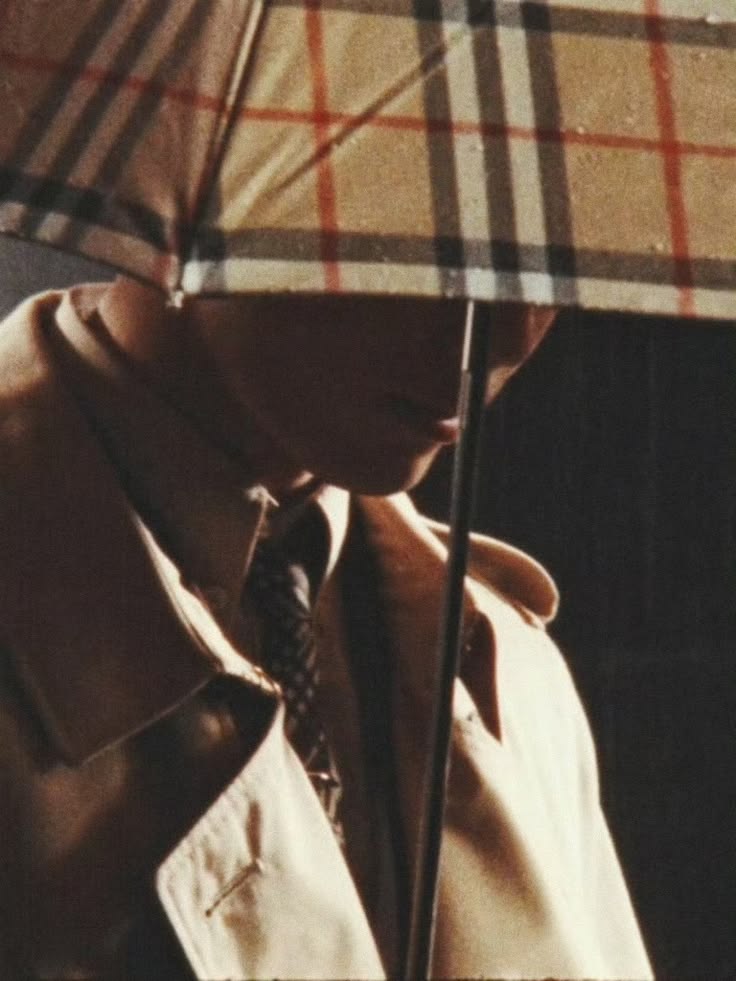 A cropped, moody shot of a face obscured under a check umbrella