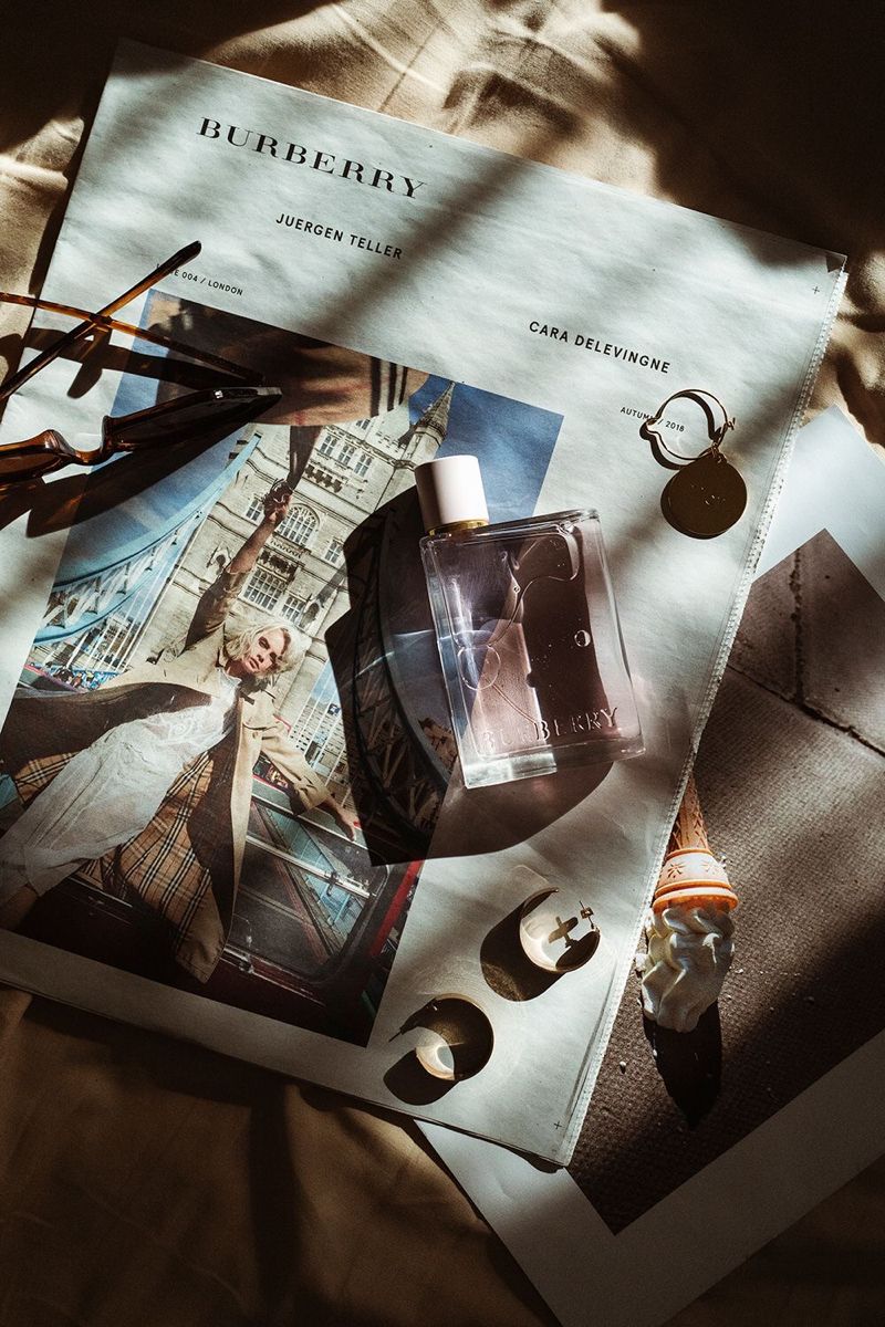 An editorial flat-lay with a Burberry magazine, perfume, and jewellery
